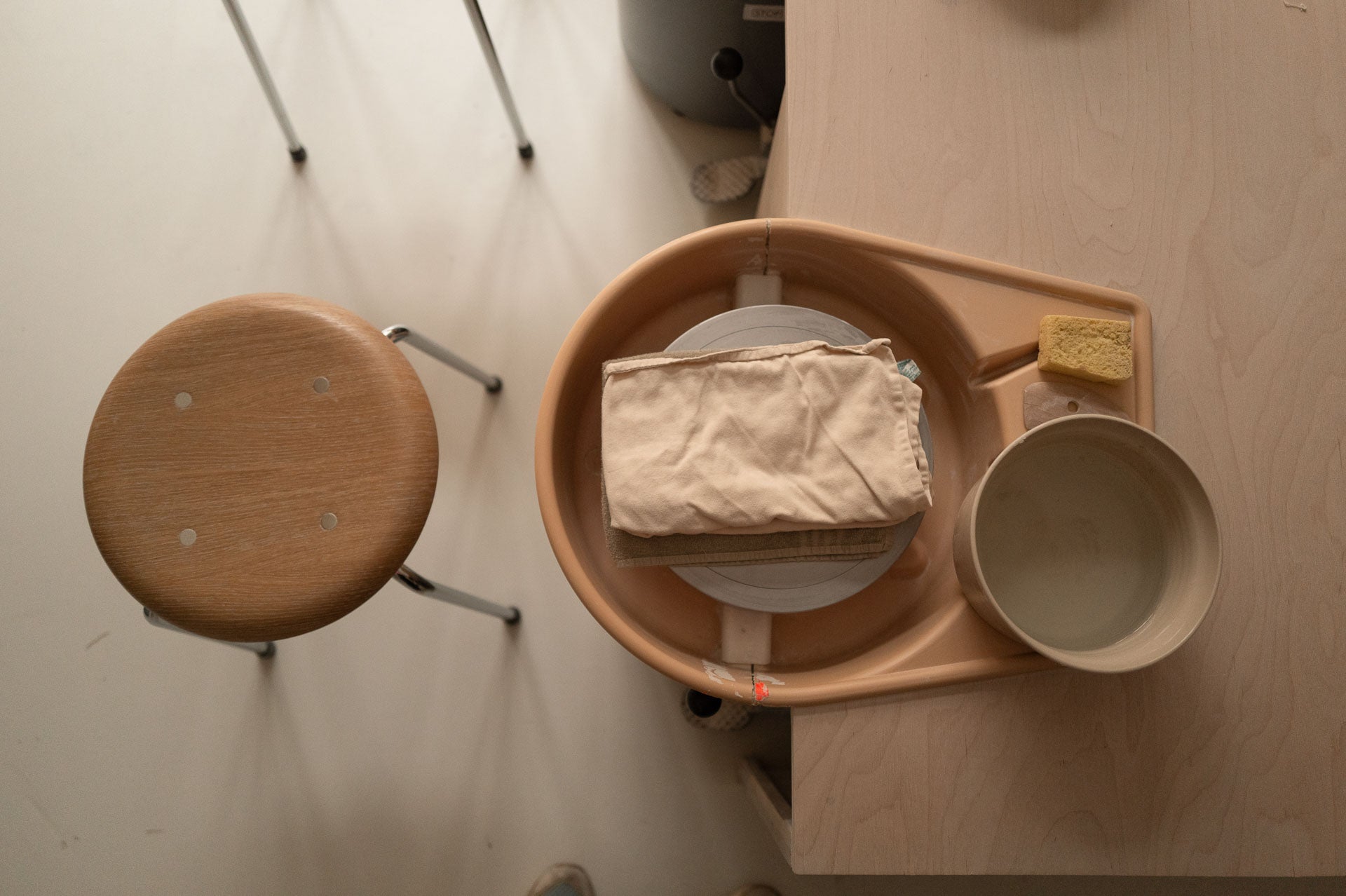 Pottery wheel setup featuring water bowls, towels, and tools for pottery class participants.