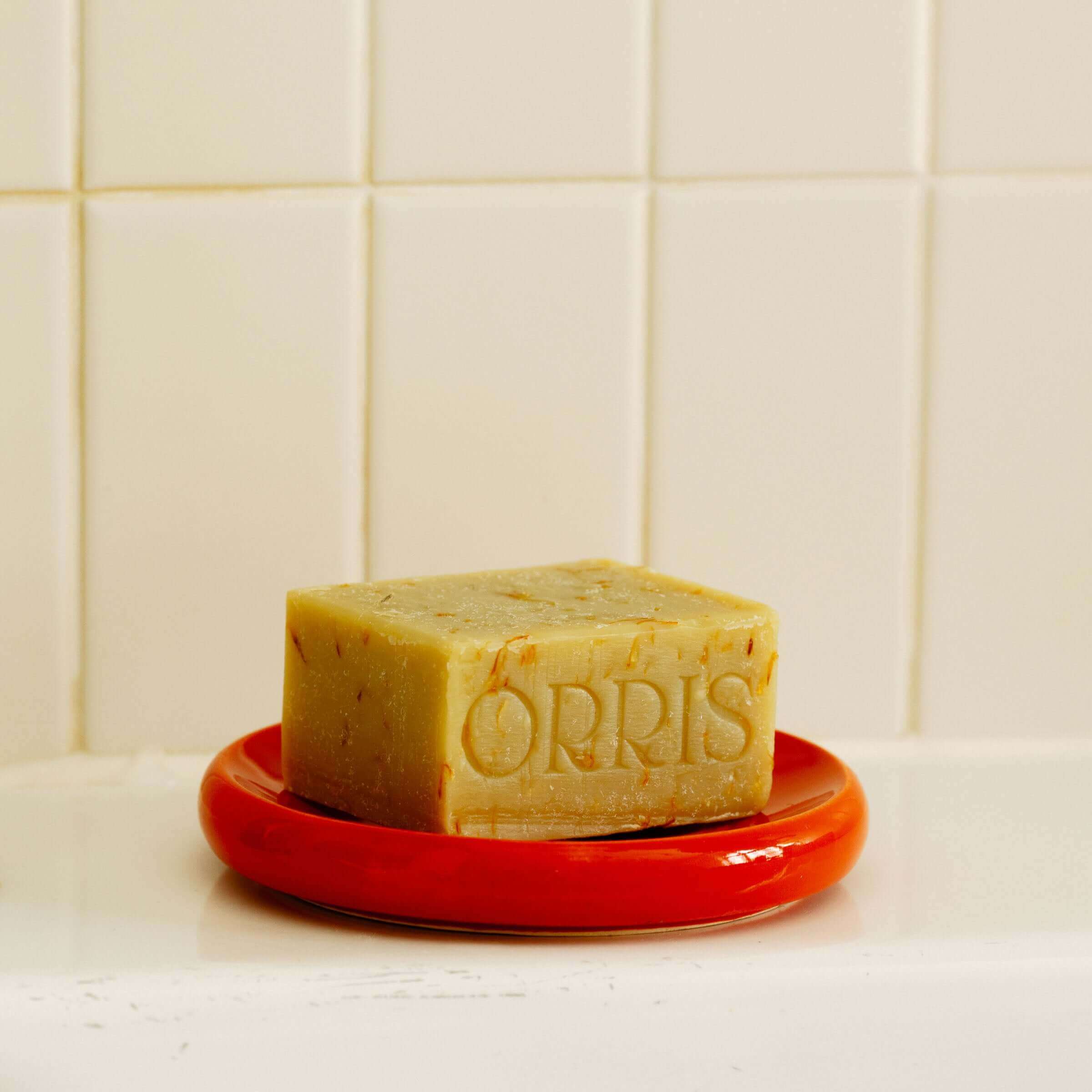 Artisanal soap on a red dish, showcasing quality and beauty for home rituals.