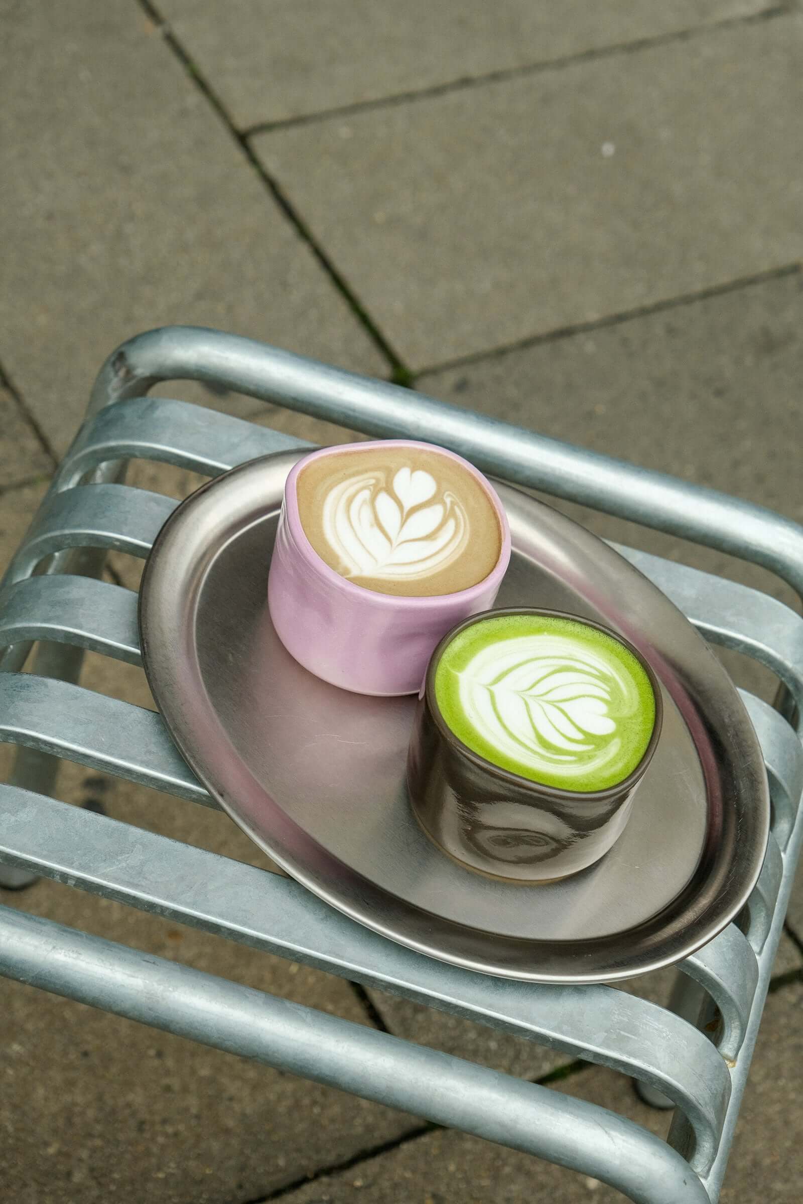 Asphaltgold Matchasome Keramikkollektion: Zwei handgefertigte Becher in Braun und Rosa auf einem silbernen Tablett.