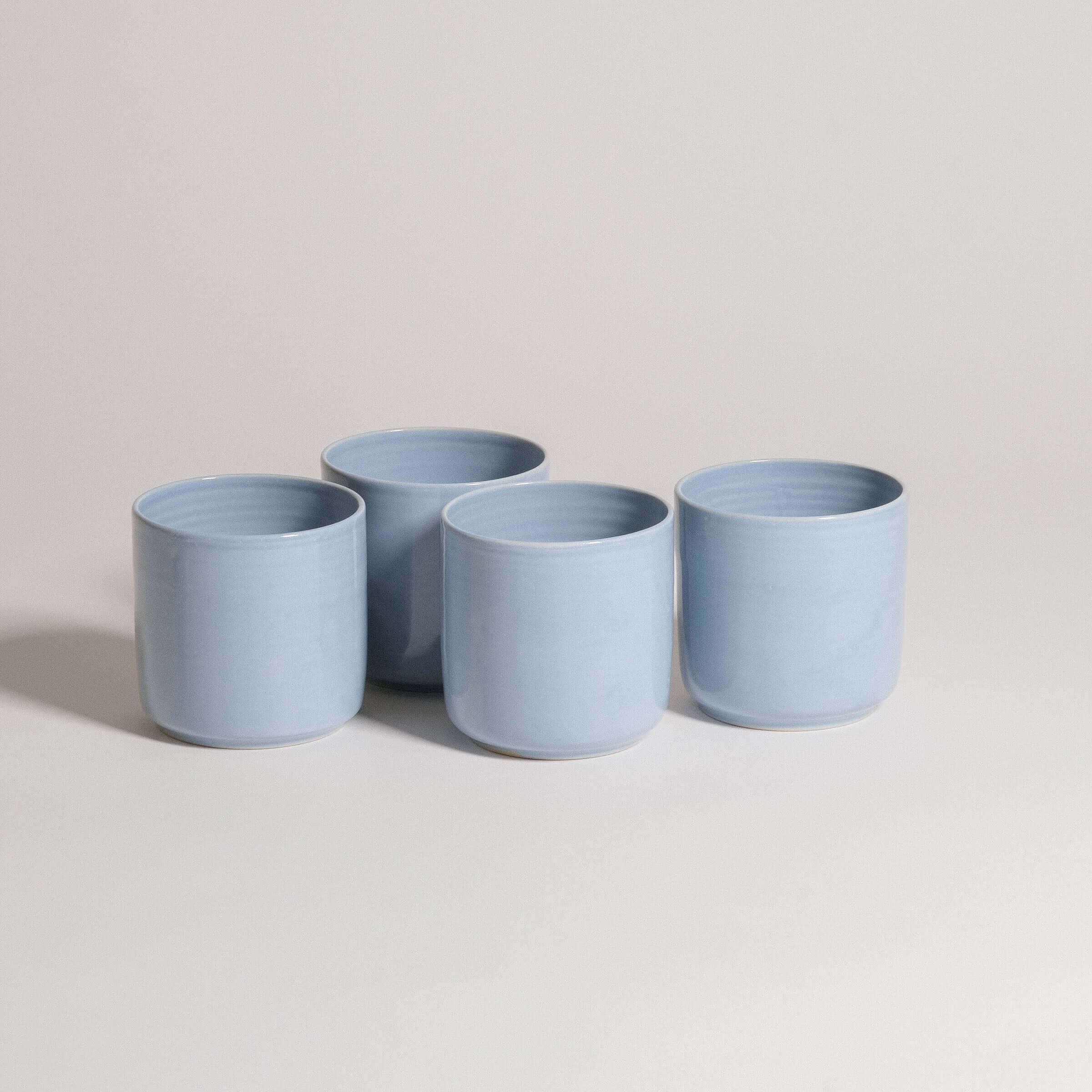 Set of four handmade blue tea cups featuring subtle shapes and soft glazes, perfect for everyday use.