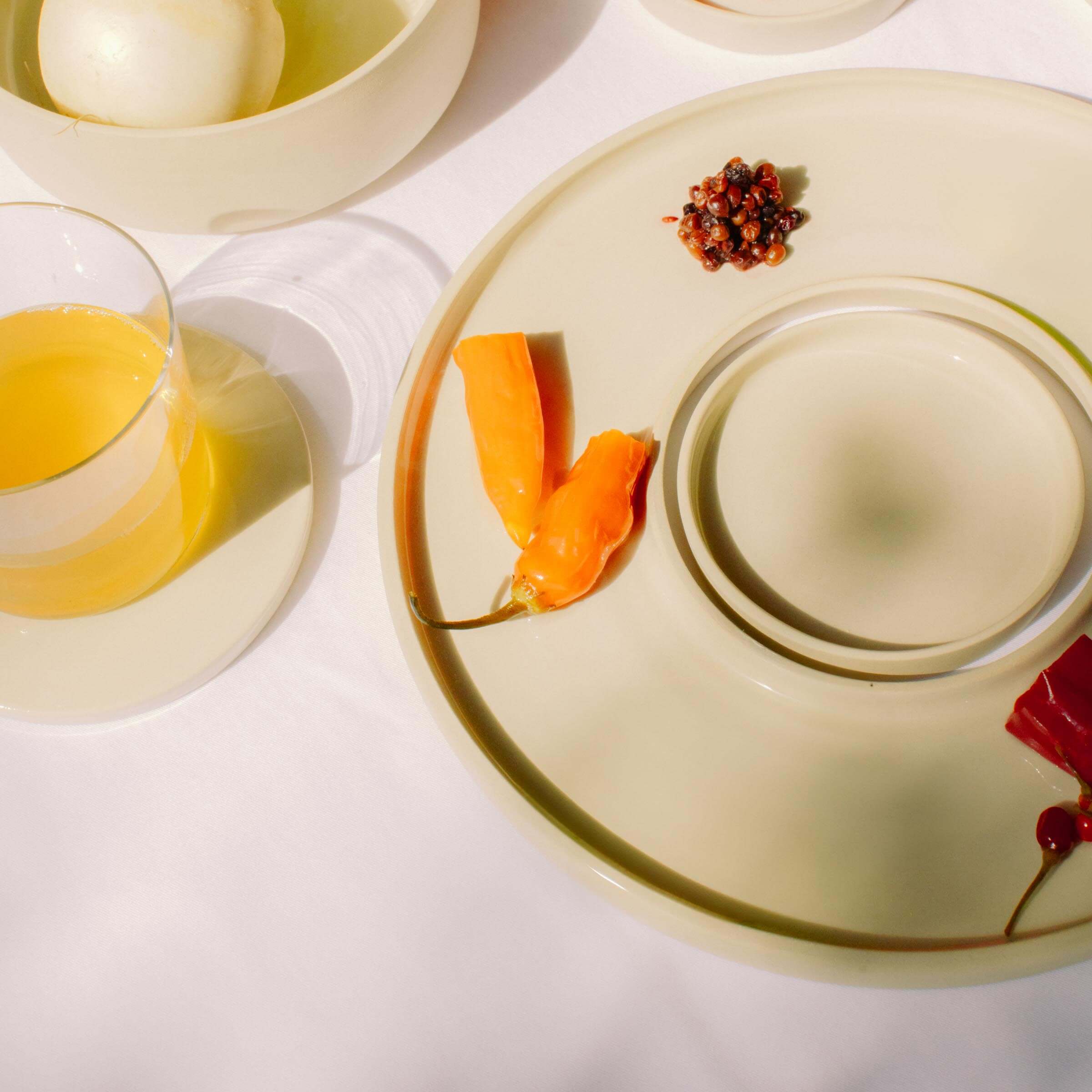 Elegant handmade ceramic trays featuring colorful peppers and a glass, perfect for serving and displaying.