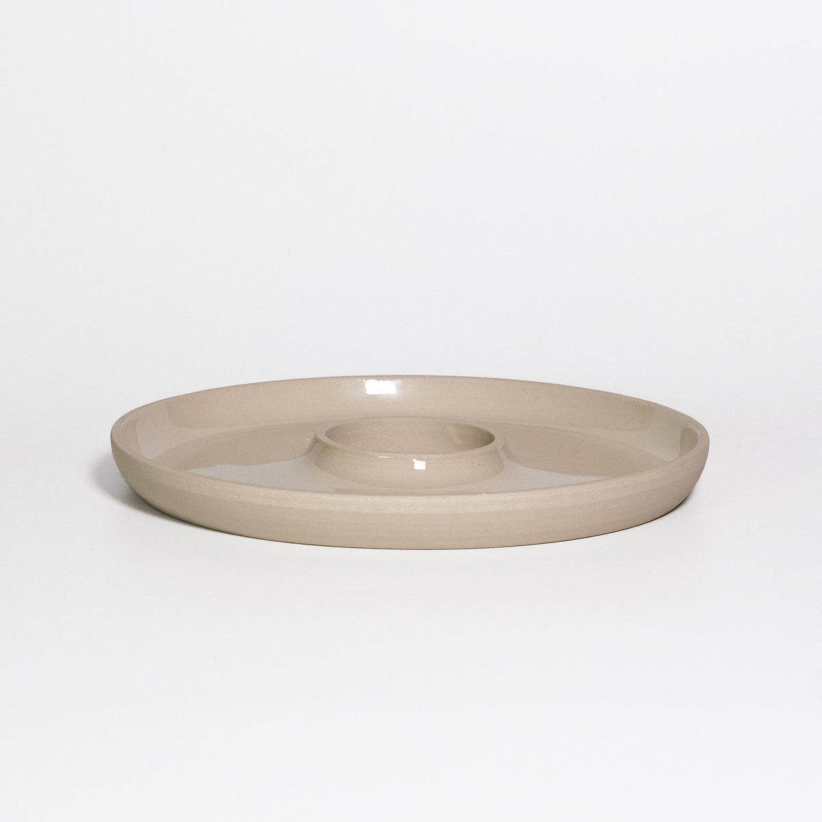 Tapas Tray Creme, round stoneware tray with a central dip well, transparent glossy glaze inside and raw clay outside