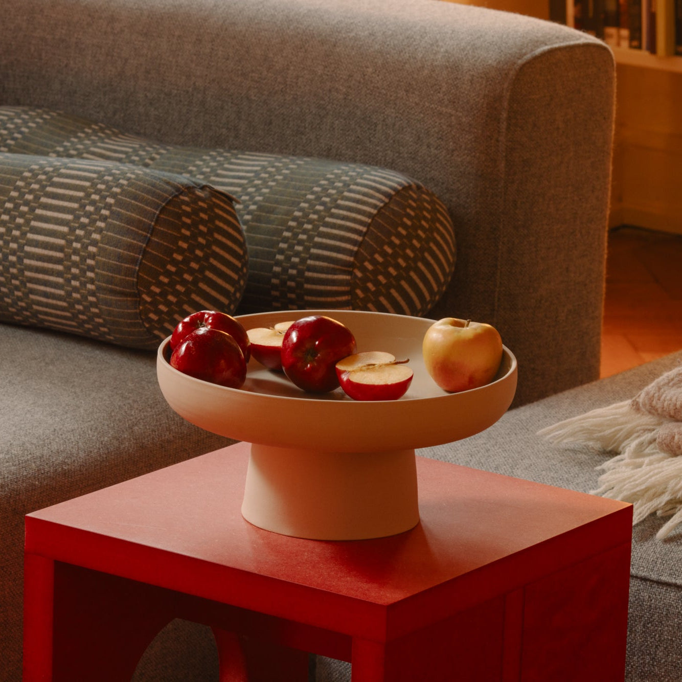 Pedestal Bowl – Aleah mit Äpfeln auf einem roten Tisch, handgemacht aus grauem Keramik. Ideale Dekoration.