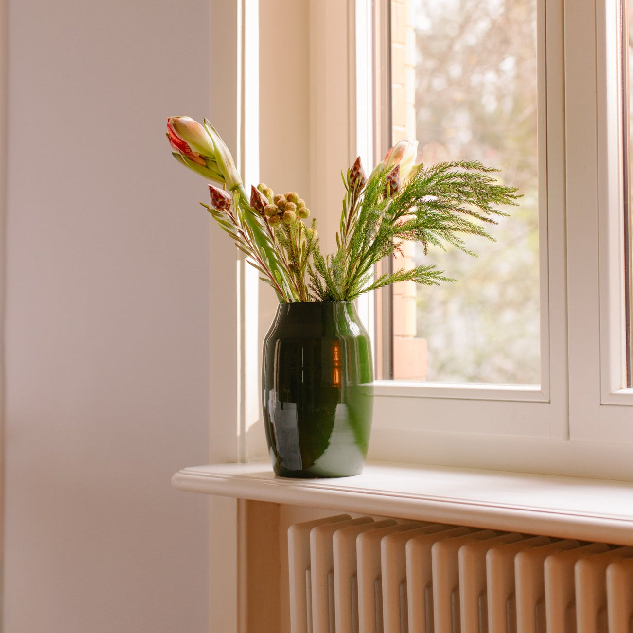 Vase with flowers on a windowsill next to a radiator