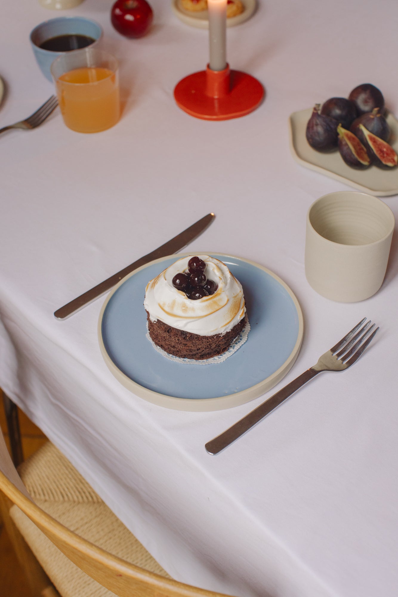 Dessert on a blue plate with a fork and knife on a white tablecloth.