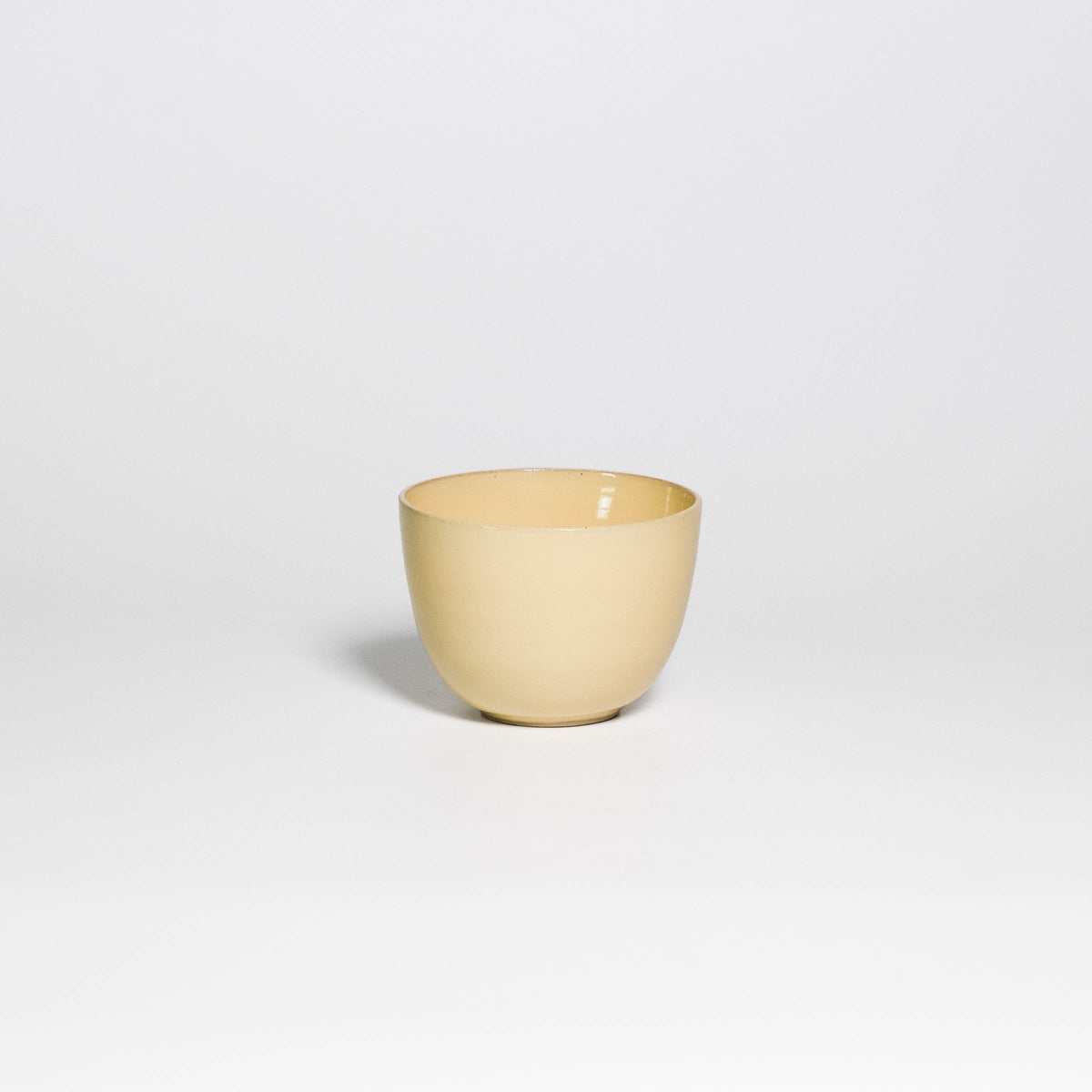 Coffee Cup Yun Yellow, handleless stoneware cup with glossy yellow glaze, front view