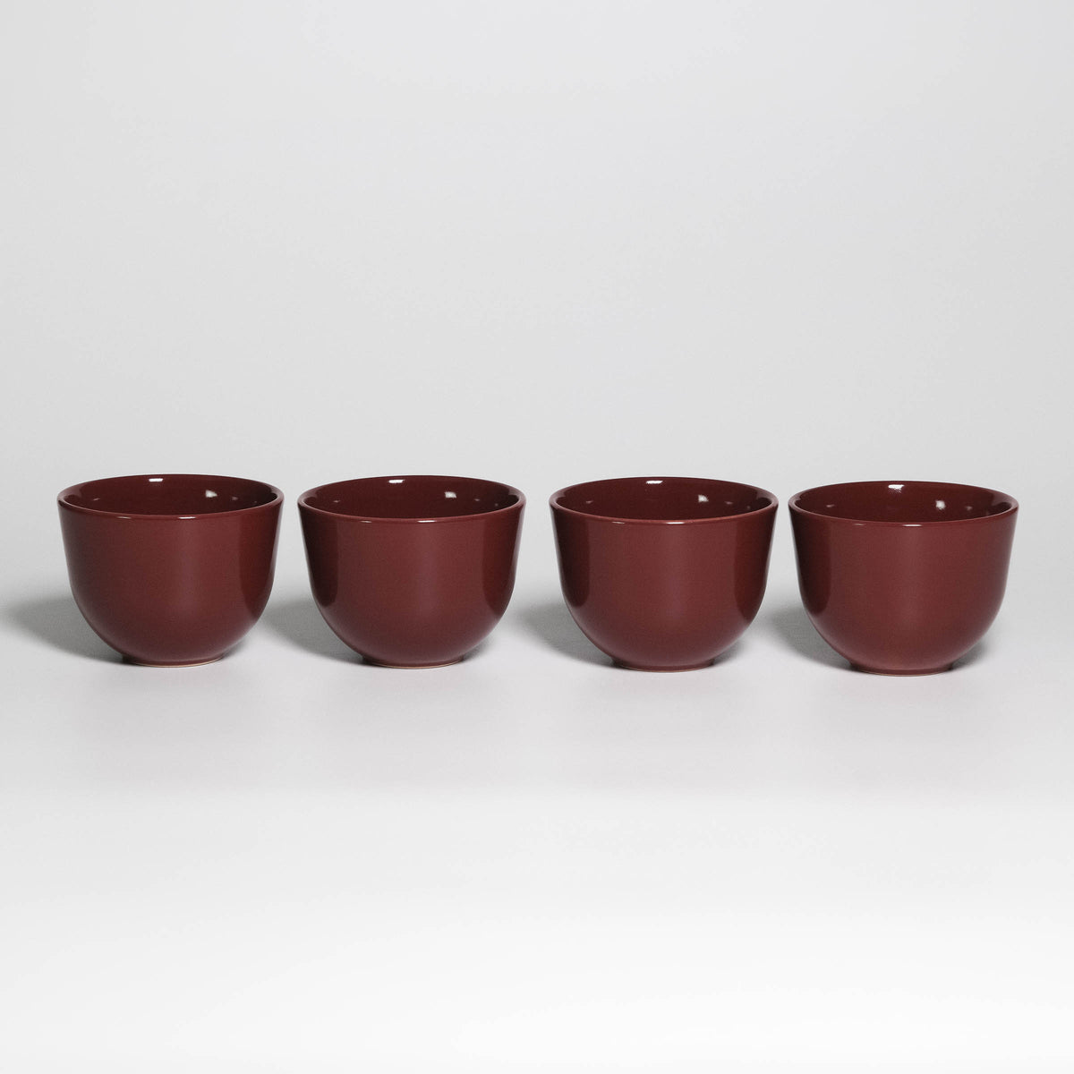 Set of 4 Coffee Cups Yun Rouge Noir, four handleless stoneware cups in a row, glossy rouge noir glaze
