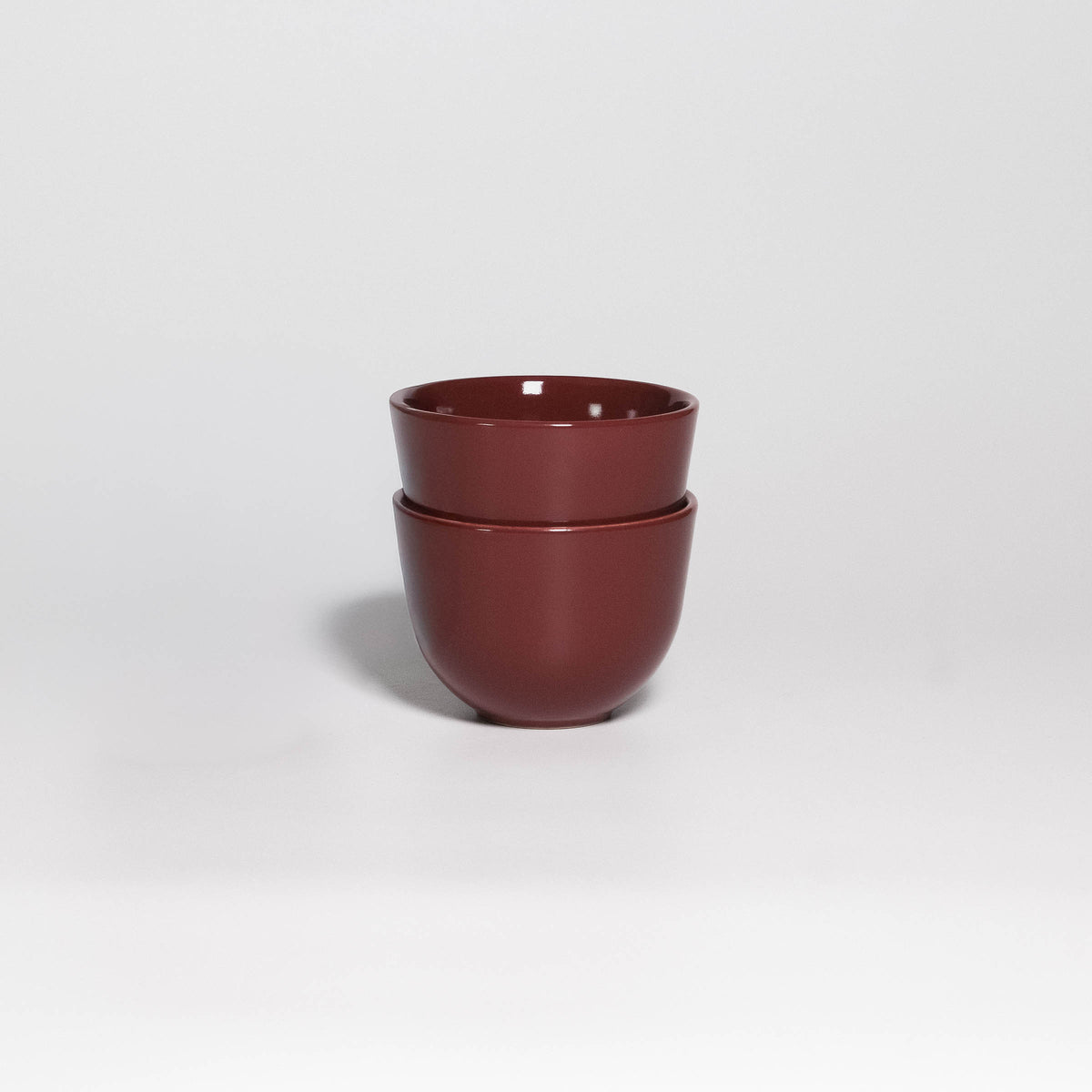 Two Coffee Cups Yun Rouge Noir stacked, handleless stoneware cups with glossy rouge noir glaze