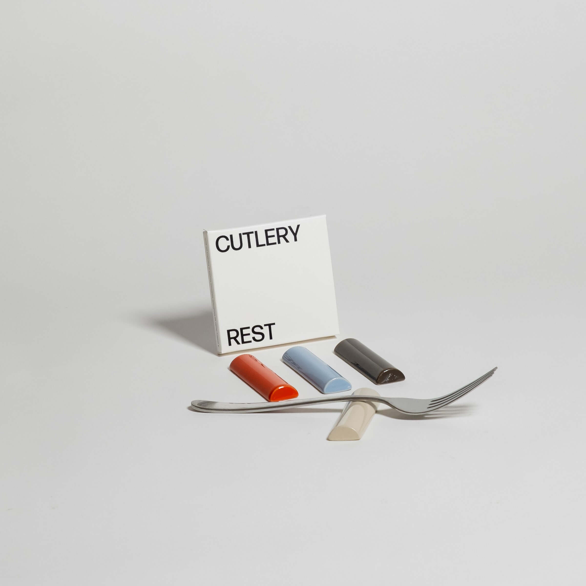 Handgefertigte Besteckablage mehrfarbig mit Gabel, Löffel und bunten Ablagen auf einem neutralen Hintergrund.