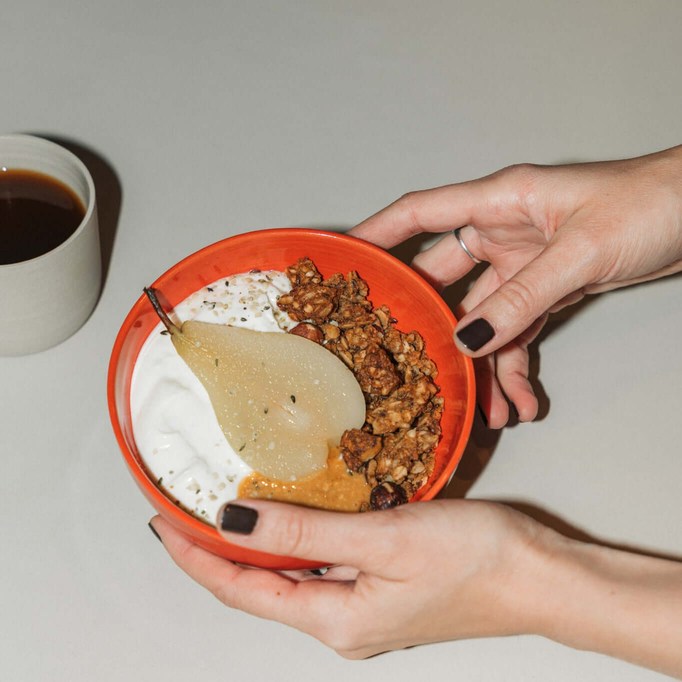 Miso granola bundle in a handcrafted bowl with yogurt and pear, accompanied by a cup of coffee.