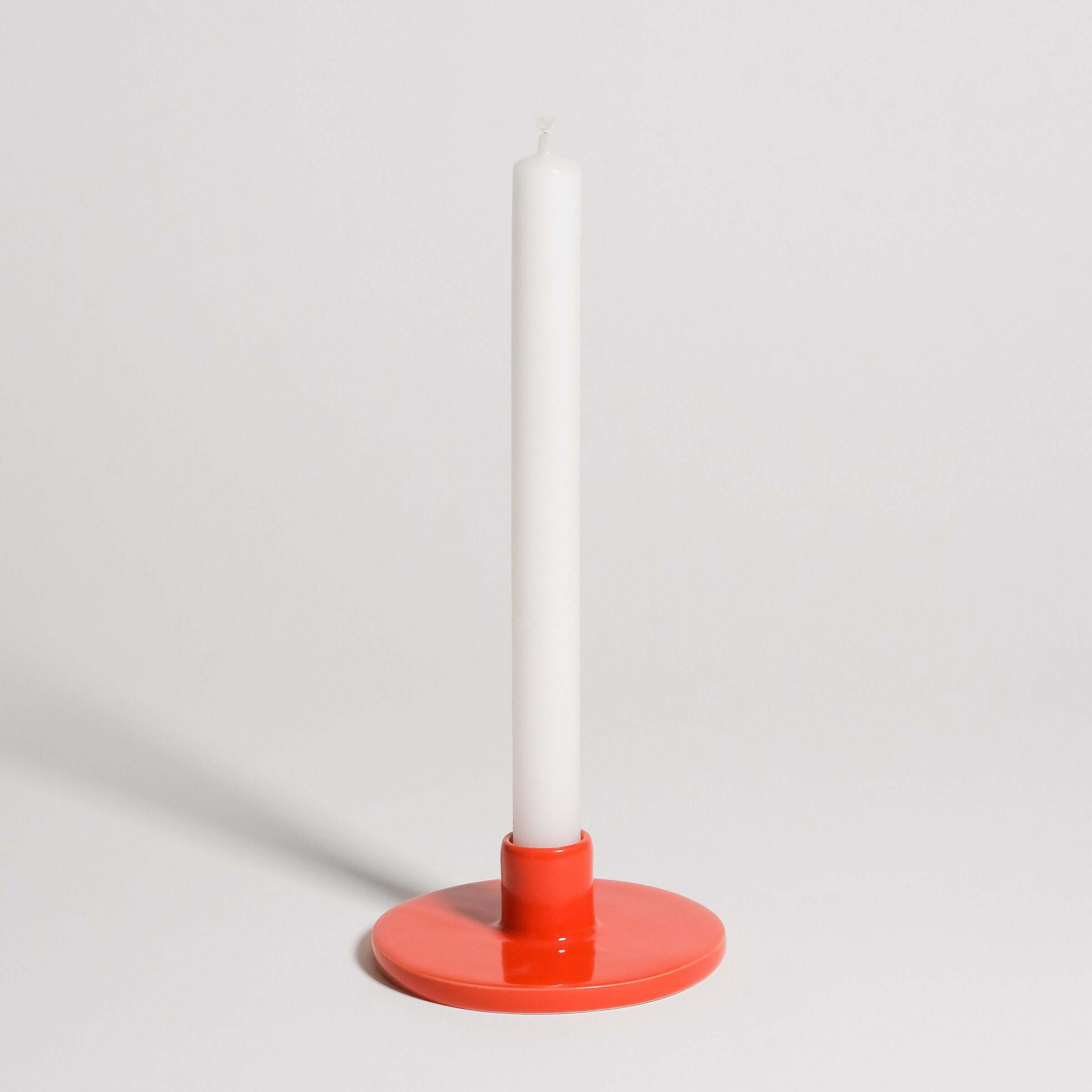 Candle Holder - Red showcasing a white candle held by a smooth, red-glazed stoneware base for modern home decor.