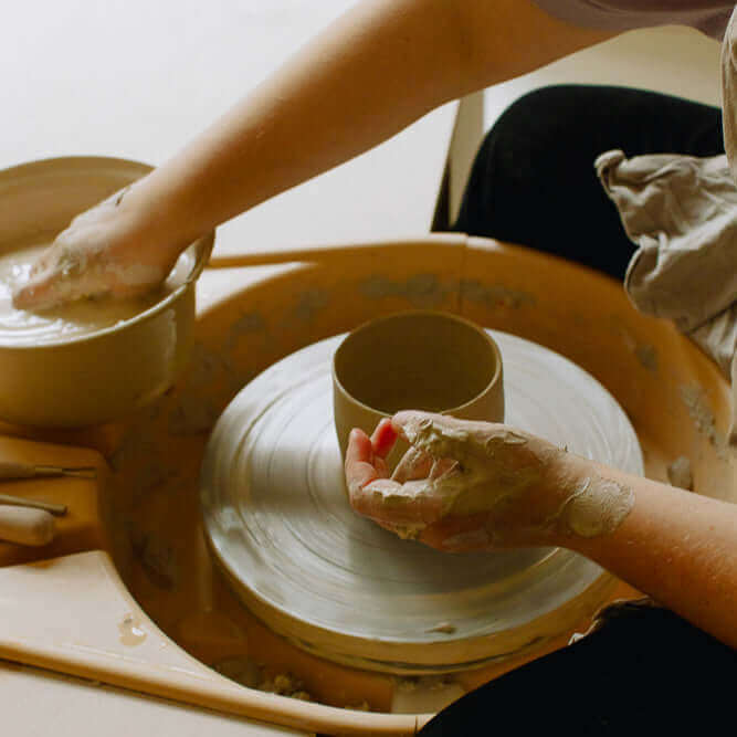 Person participating in a Gift Making Class at a pottery wheel, creating handmade pottery.