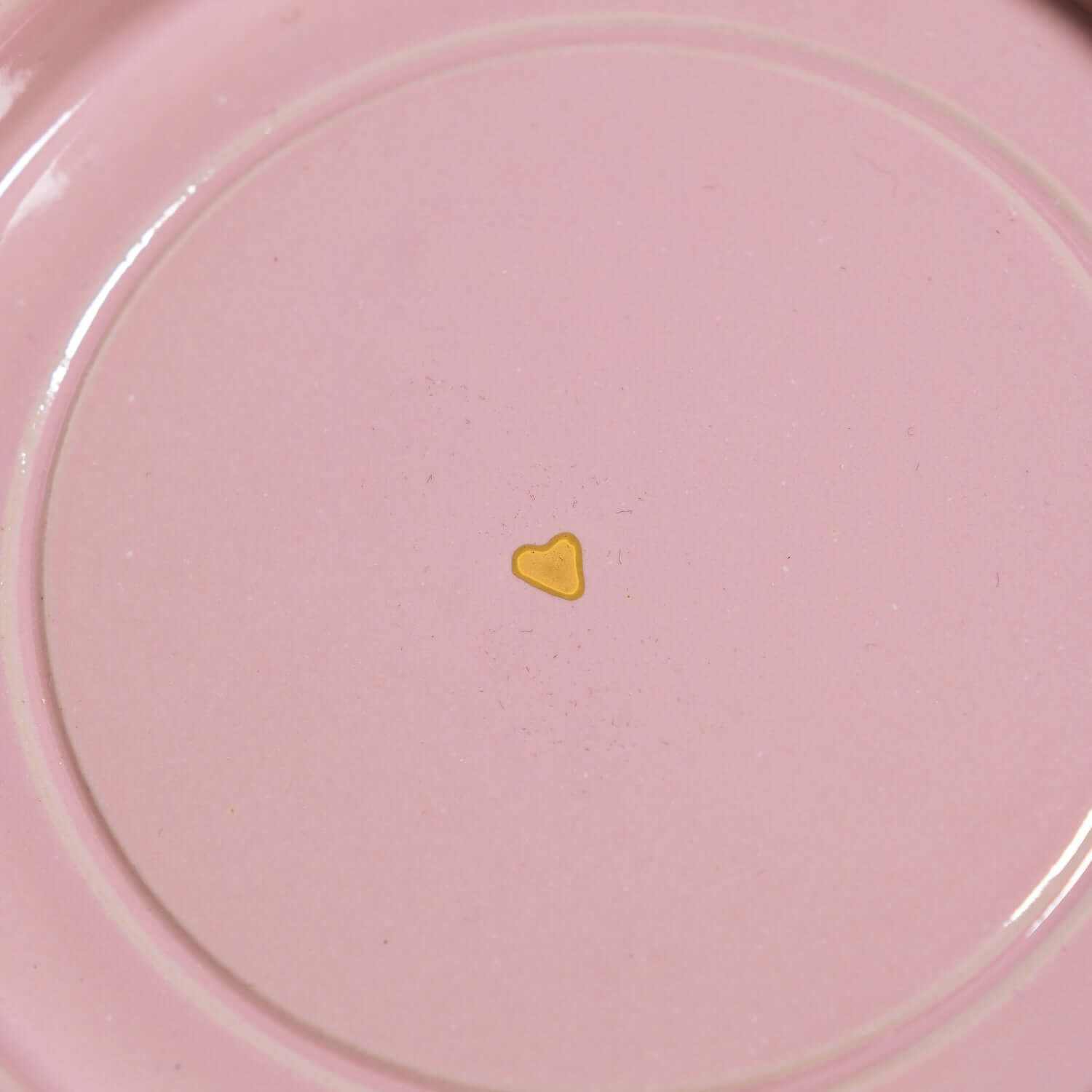 Detail der Handgemachte Keramik Untertasse mit goldenen Herzen auf rosa Hintergrund.