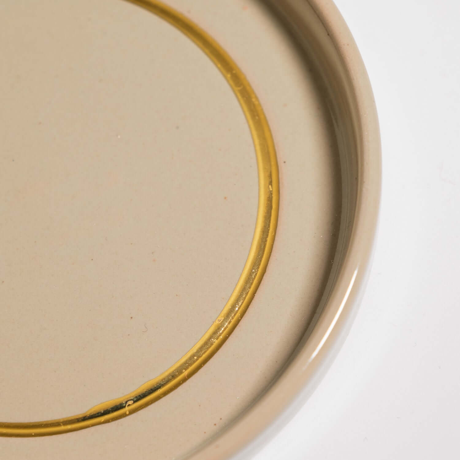 Handgemachte Keramik Untertasse in Salbei mit handgemaltem Golddetail auf der Oberfläche.