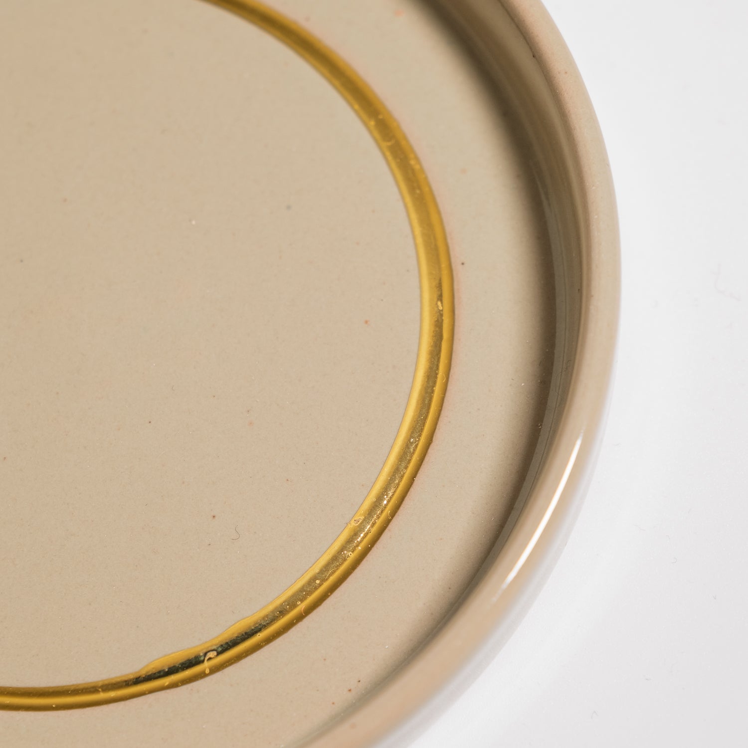Handgemachte Keramik Untertasse in Salbei mit handgemaltem Golddetail auf der Oberfläche.