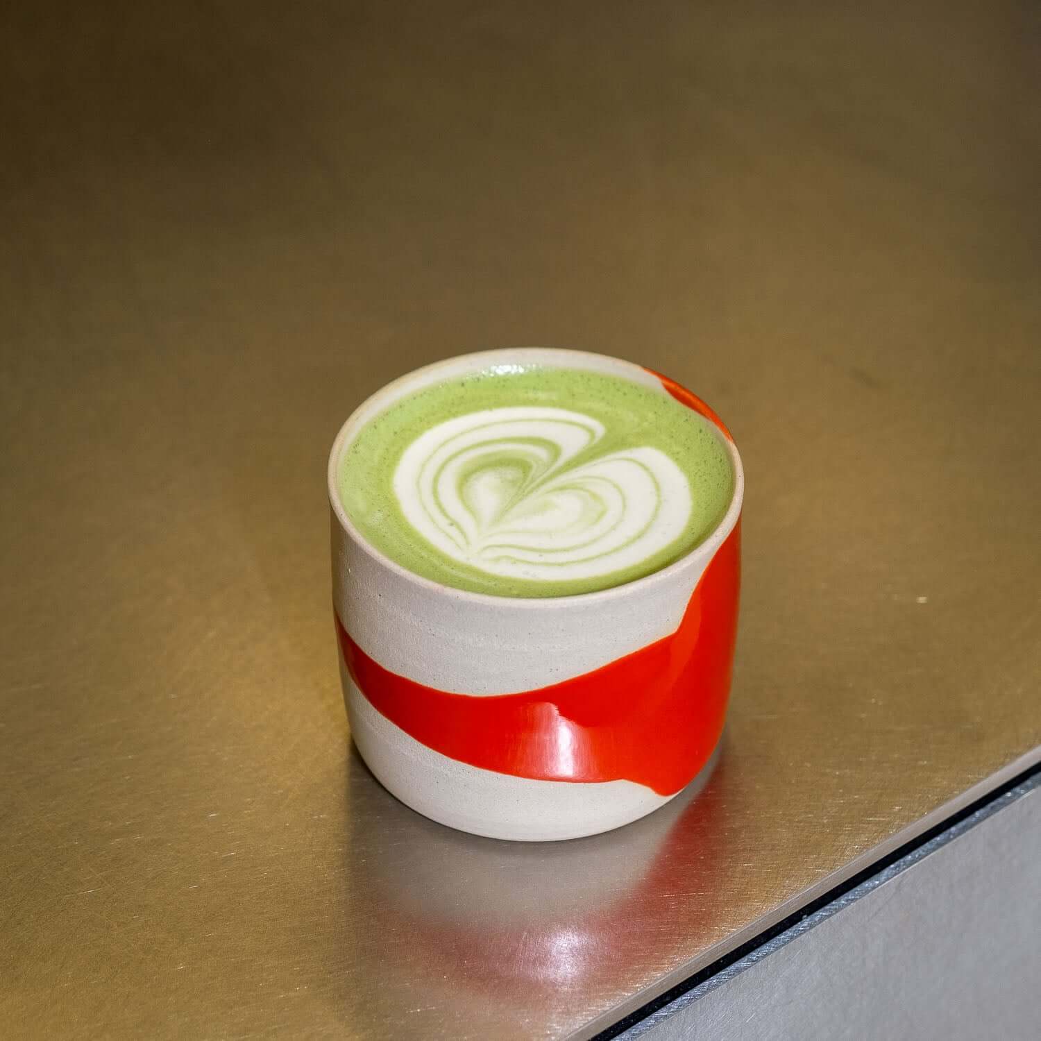 handgemachter Kaffeebecher Splash Rot mit grüner Teetasse und Herzmuster auf der Oberfläche.