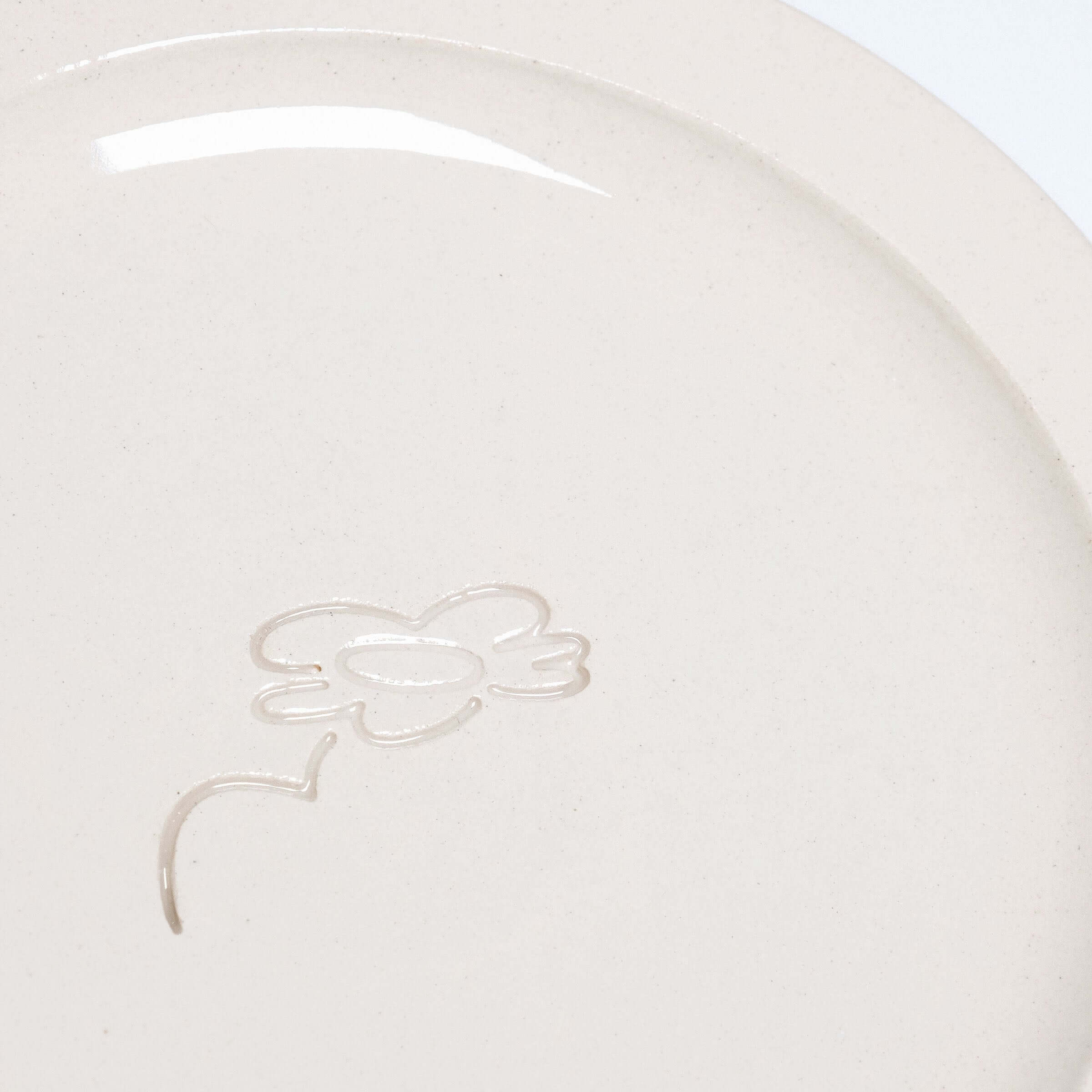 Close-up of neo creme bistro plate showcasing embossed logo and smooth glaze finish on durable stoneware.