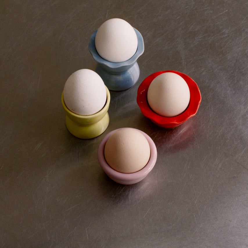 Handgemachter Eierbecher aus Steinzeug in verschiedenen Farben mit Eiern.
