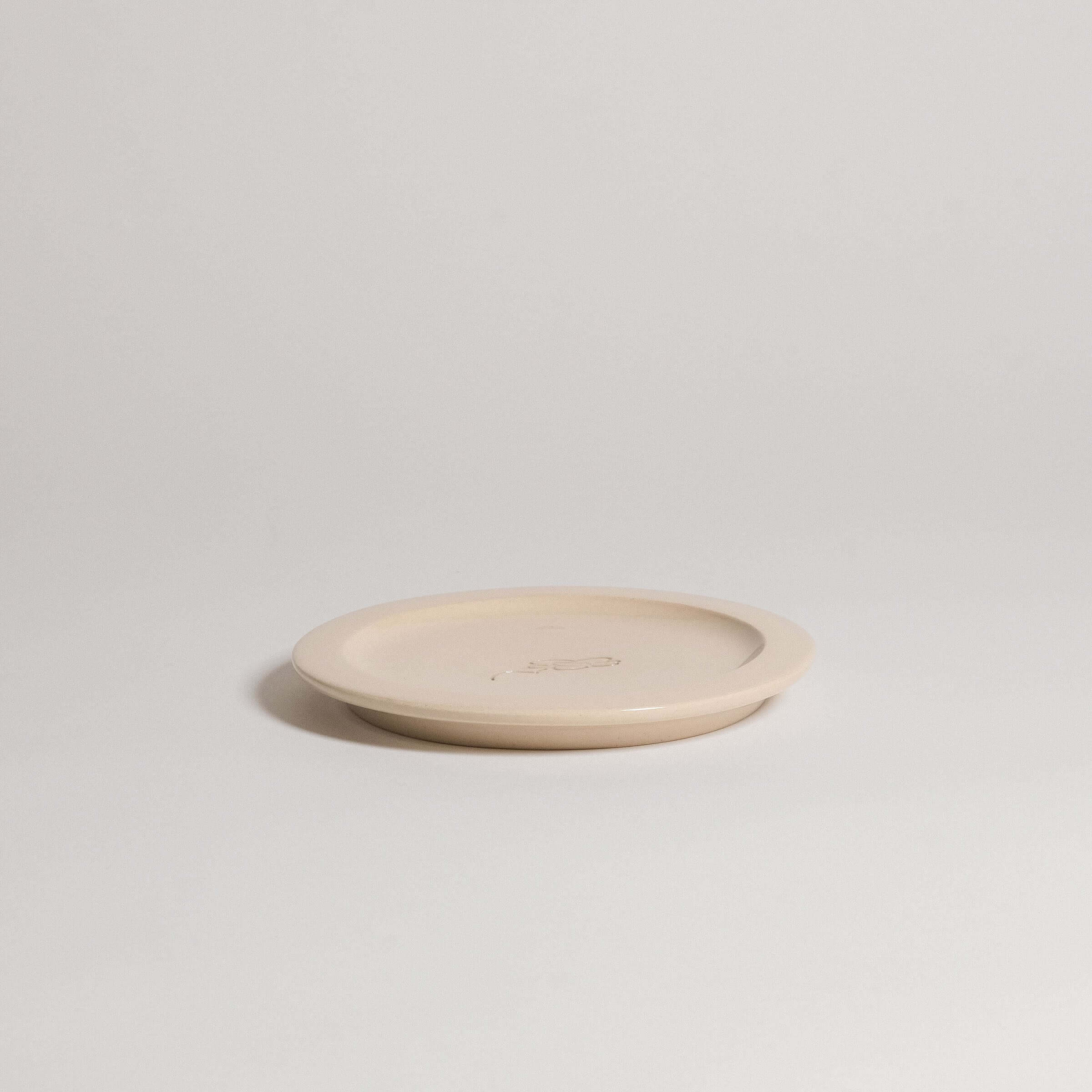 Handcrafted Neo Creme bistro plate in durable stoneware with embossed logo, showcasing transparent glaze and unique character.