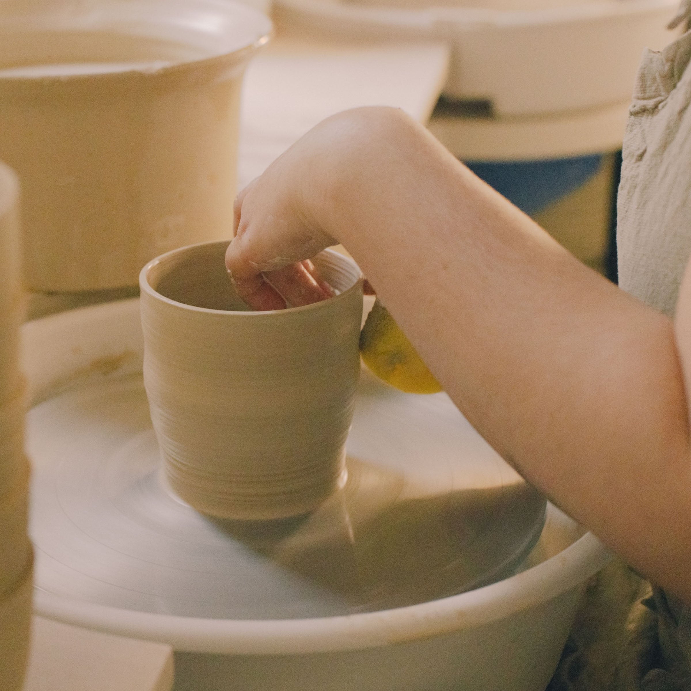 Hand beim Drehen eines Tontasse im fortgeschrittener drehscheiben töpferkurs.