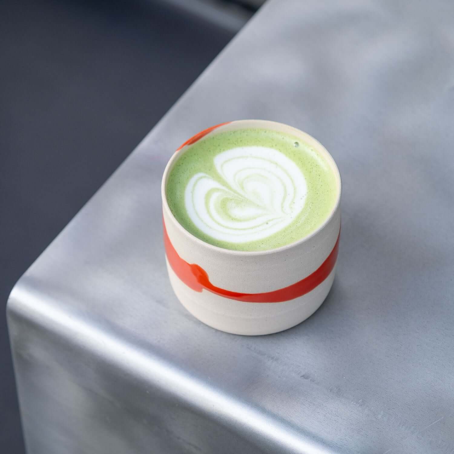 4er Set Kaffeebecher Splash Rot mit grünem Getränk auf Tisch, handgefertigter Kaffeebecher aus Frankfurt.