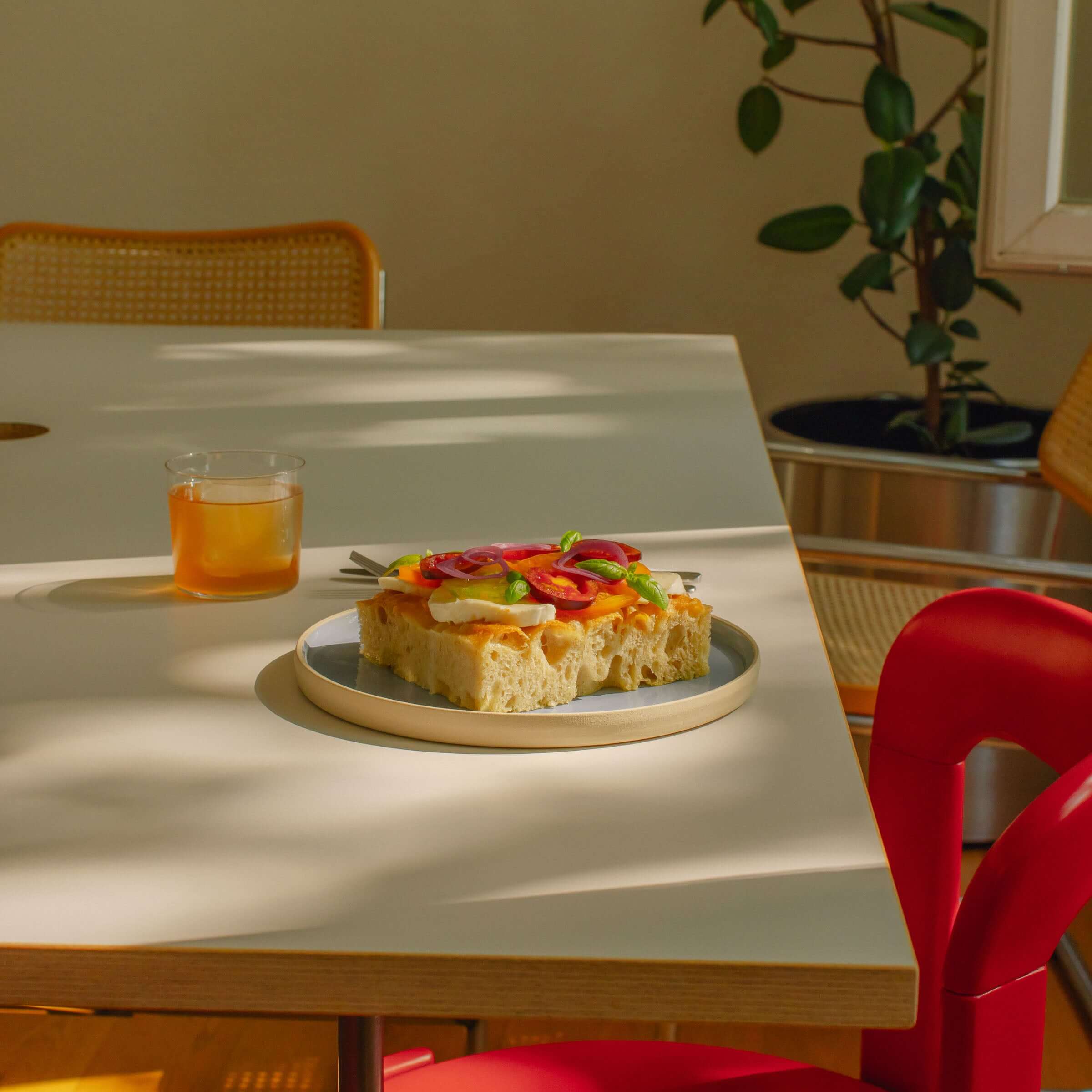 A delicious sandwich on a medium Iceblue dinner plate, set on a stylish dining table with a drink.