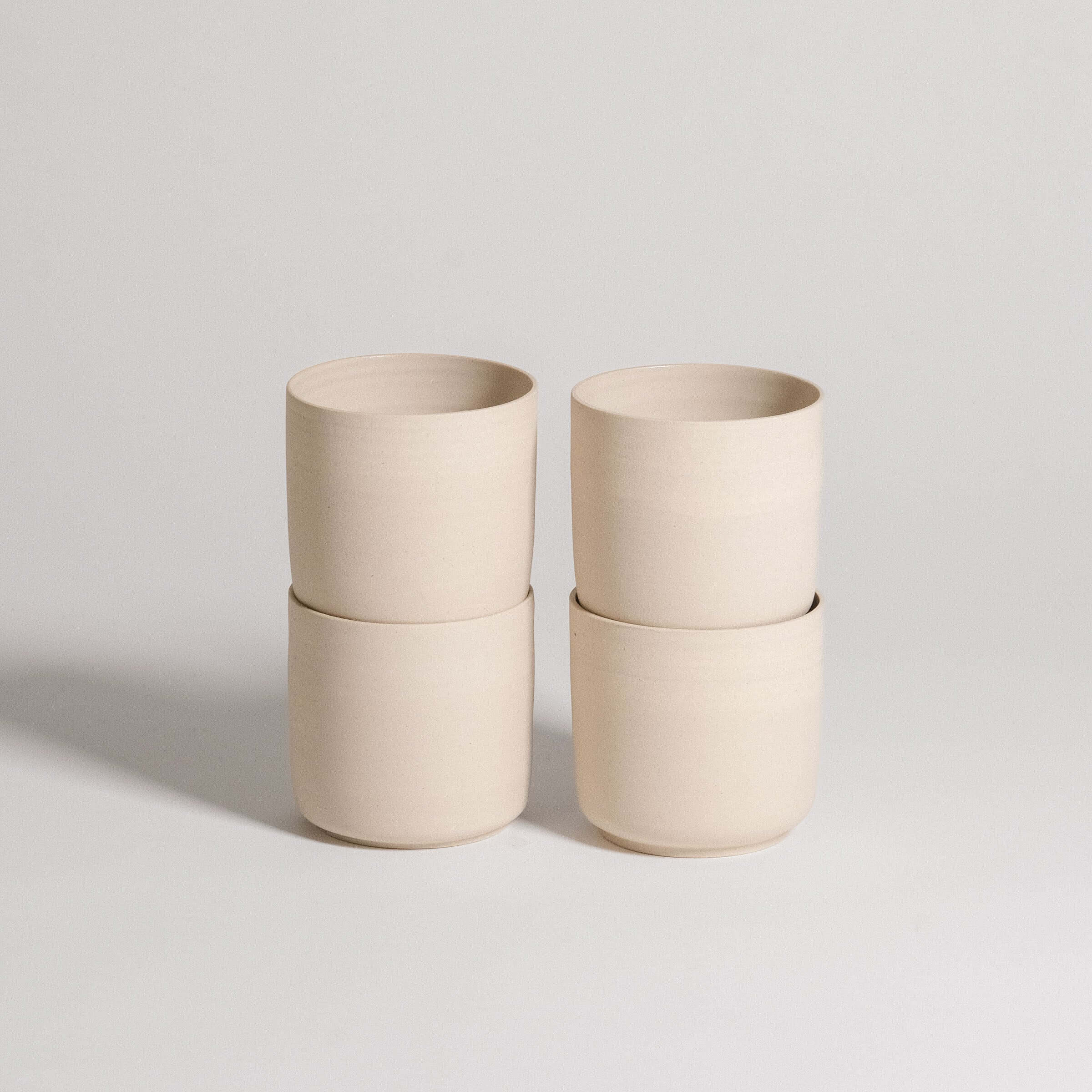 Set of 4 Nomi Creme tea cups made of grey stoneware with glossy interior and raw exterior finish.