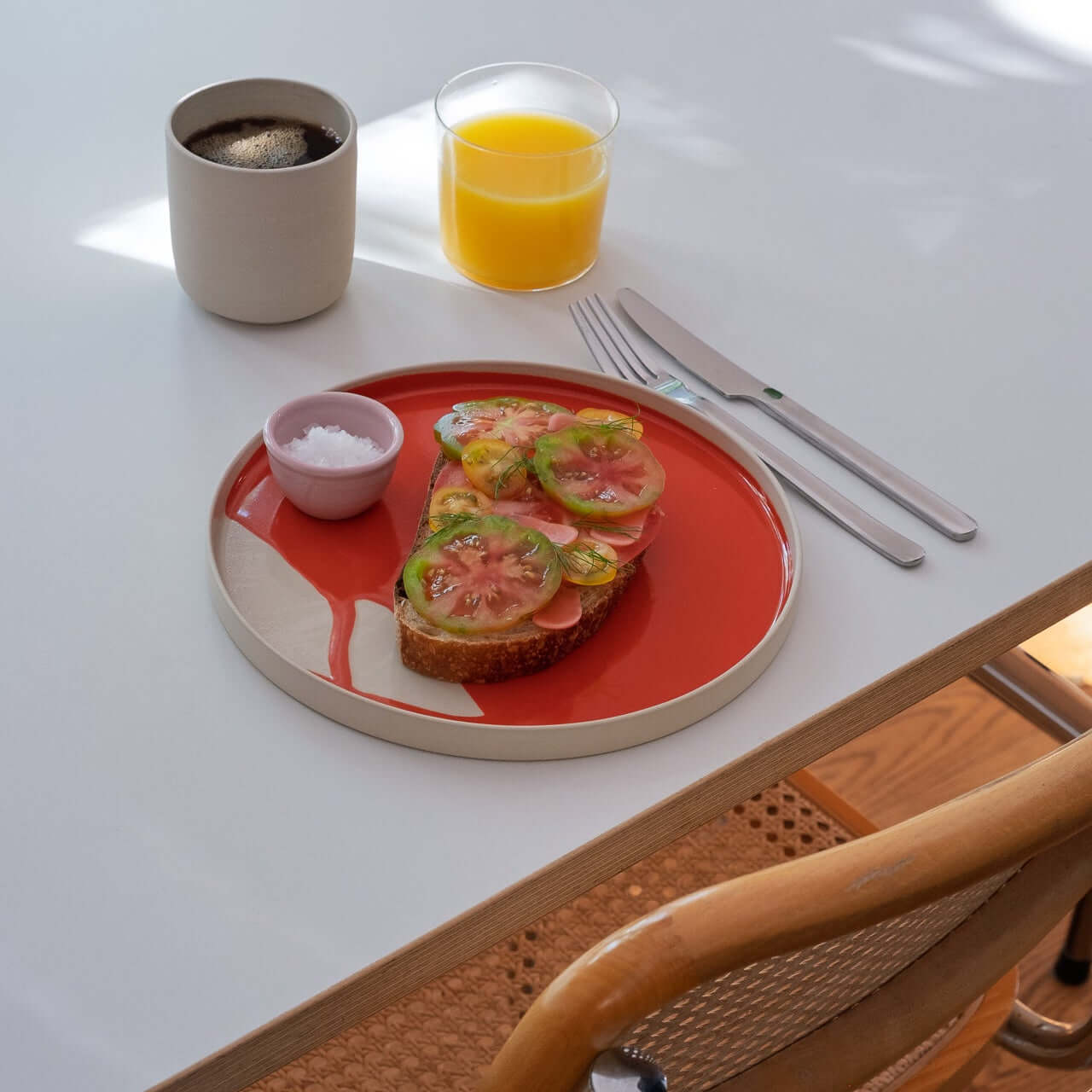 Dinner Plate – Splash Red mit Brot, Tomaten, Joghurt und Getränken auf einem Tisch.