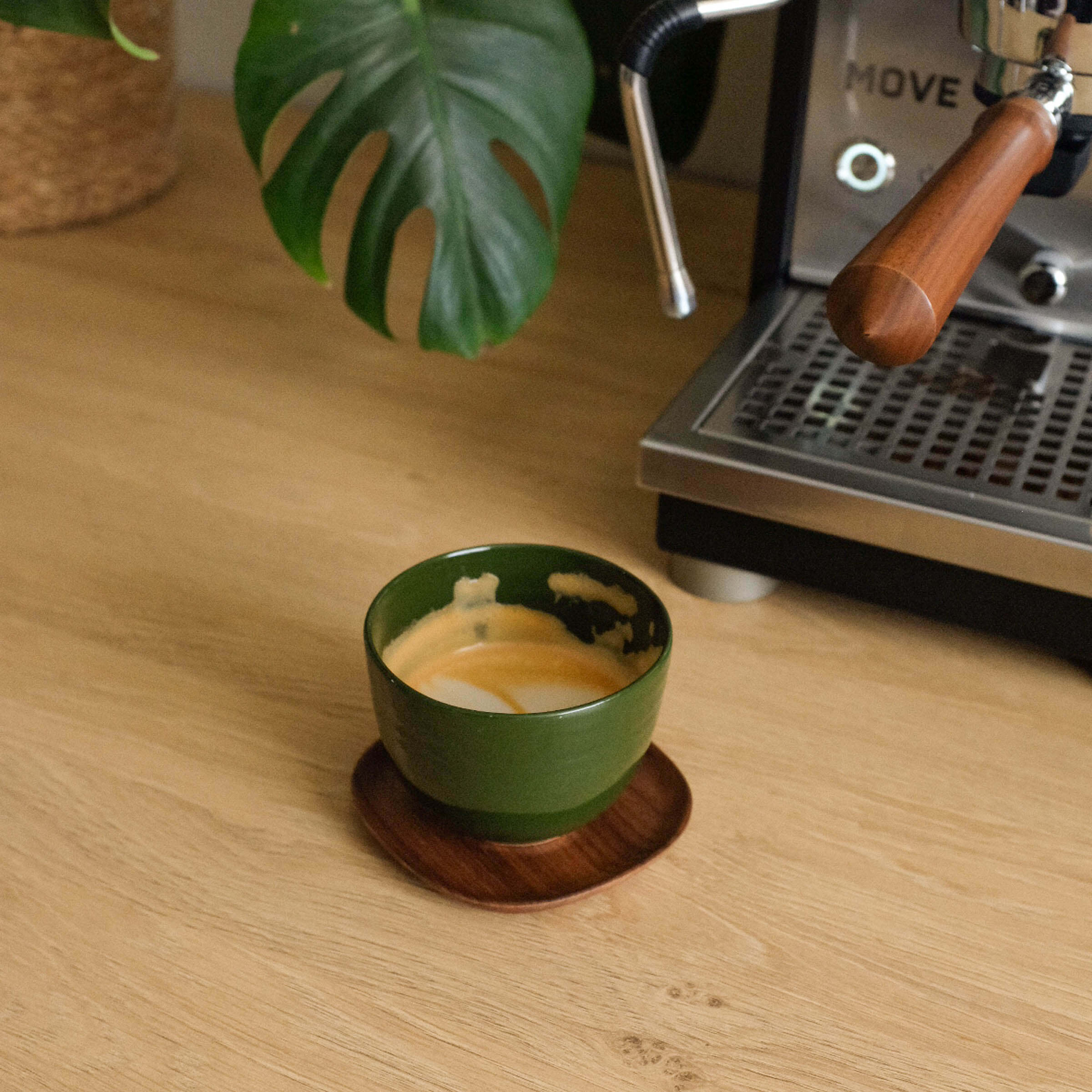 Handcrafted Yun green coffee cup from stoneware ceramic with espresso, placed on a wooden saucer.