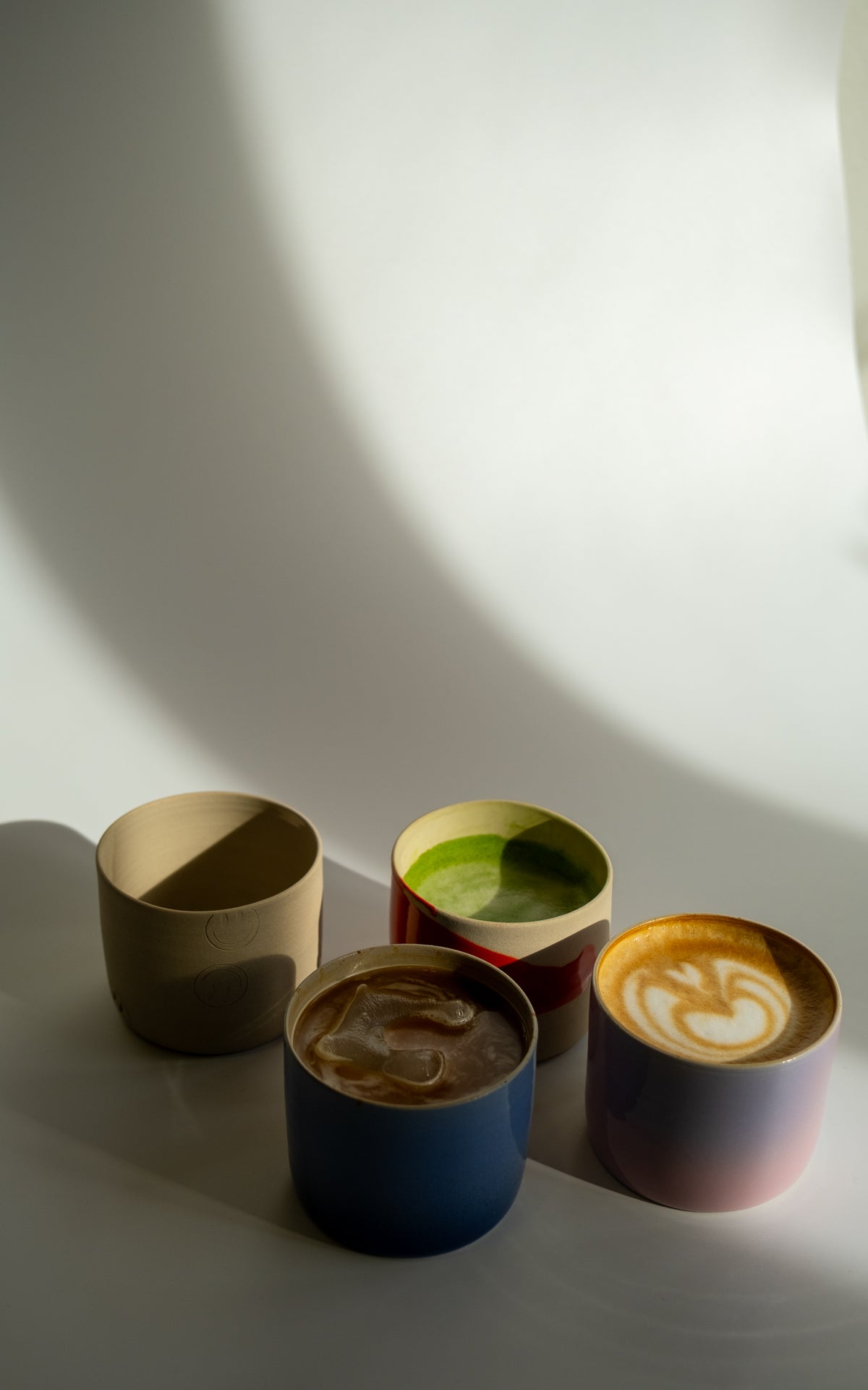 Verschiedene handgemachte Keramik Tassen der Happy Edition handgemachte Keramik mit Getränken.