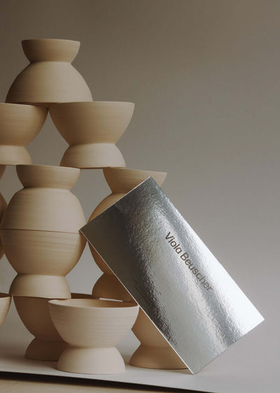 Printed gift card beside stacked wooden pottery bowls in a minimalist setting.