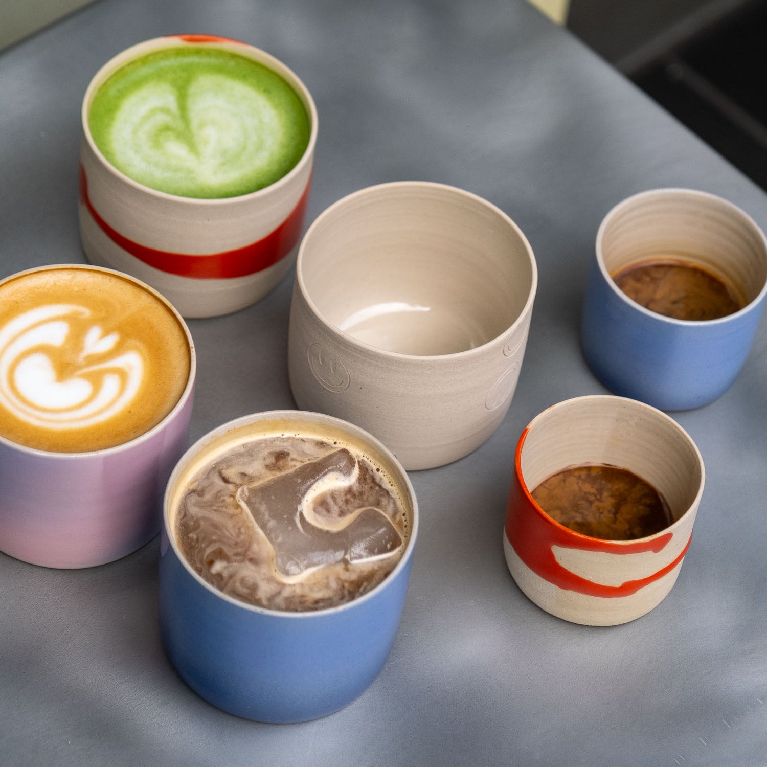 Blauer Verlauf Kaffeebecher in verschiedenen Größen und Farben auf einem Tisch, perfekt für Kaffee und Tee.