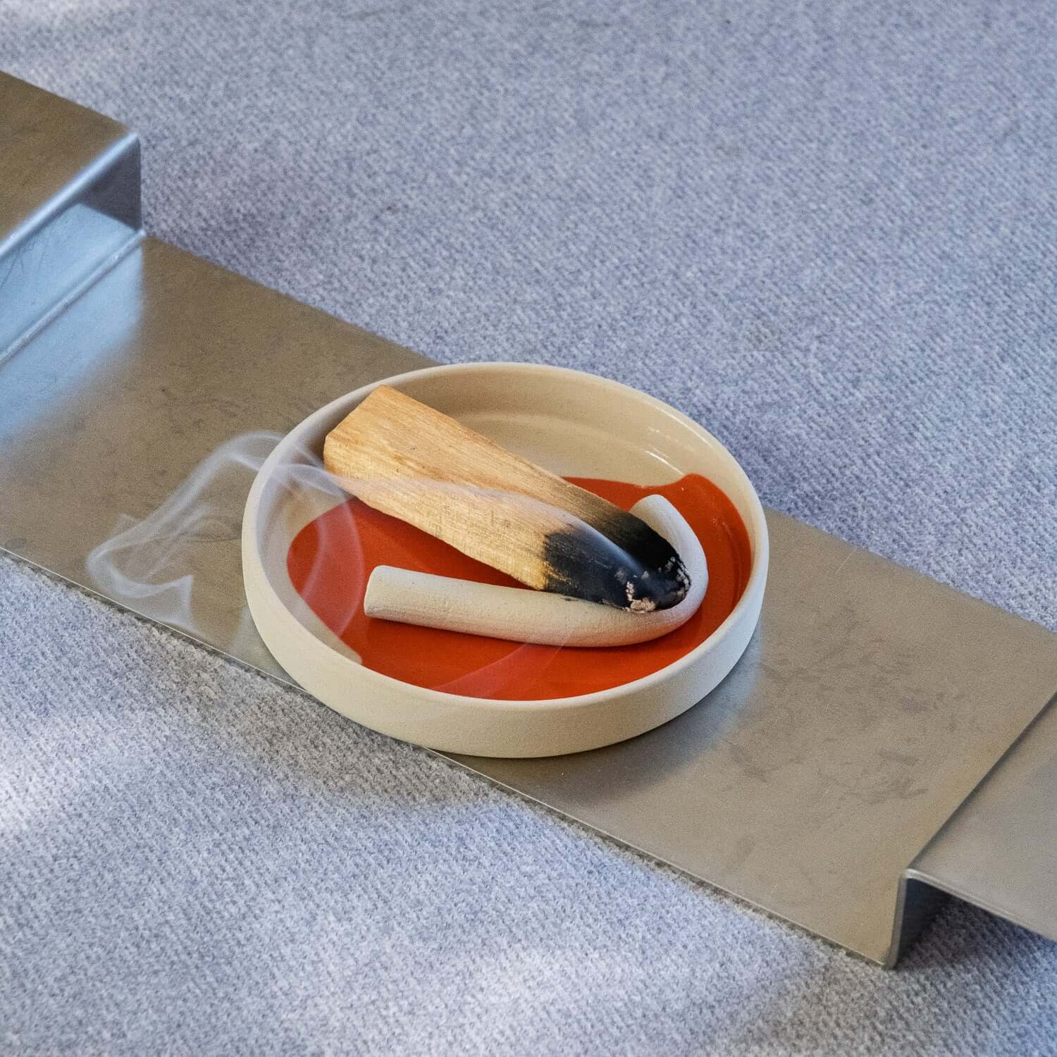 Saucer - Splash Red mit Räucherwerk und Holz auf einem modernen Tisch.