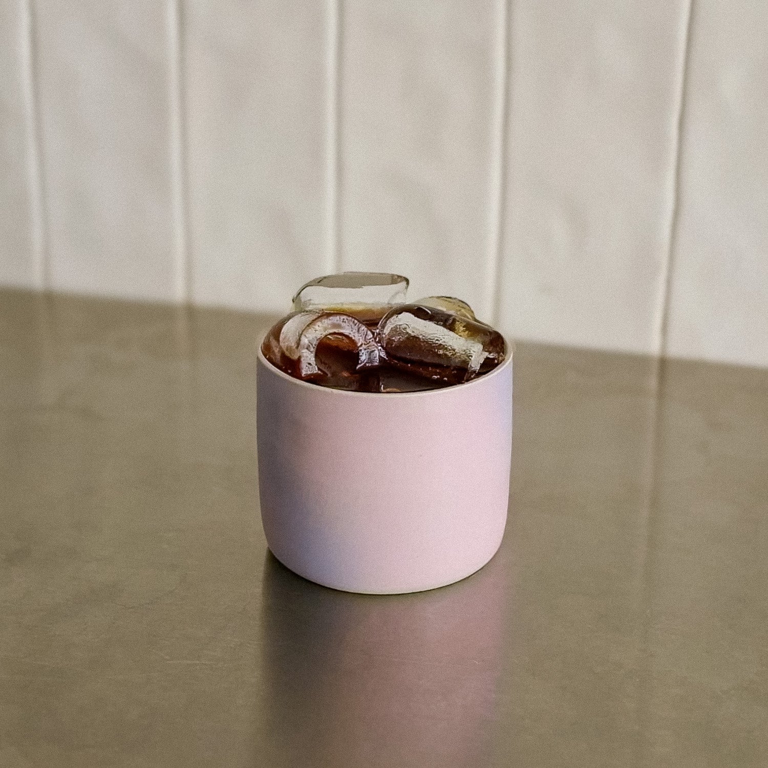Coffee Cup - Lilac Sky mit bunten Eiswürfeln auf einer Tischfläche.