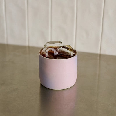 Coffee Cup - Lilac Sky mit bunten Eiswürfeln auf einer Tischfläche.