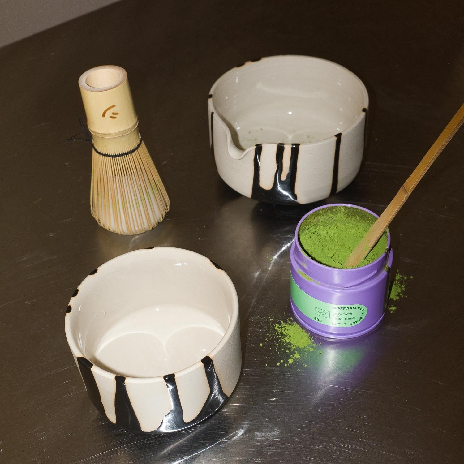 Matcha Set – Otis mit handgemachtem Schalen, matcha Quirl und grünem Matcha-Pulver auf Edelstahloberfläche.