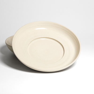 Weite flache cremefarbene Schale – schräge Ansicht mit konzentrischen Ringen innen.