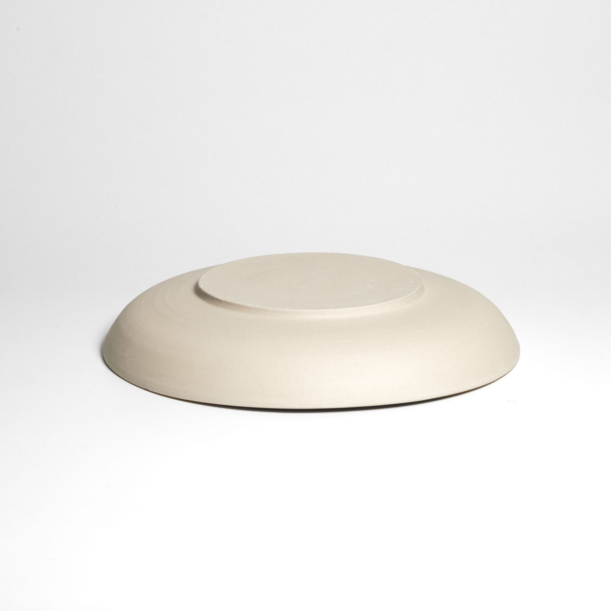 Weite flache cremefarbene Schale – Unterseite.