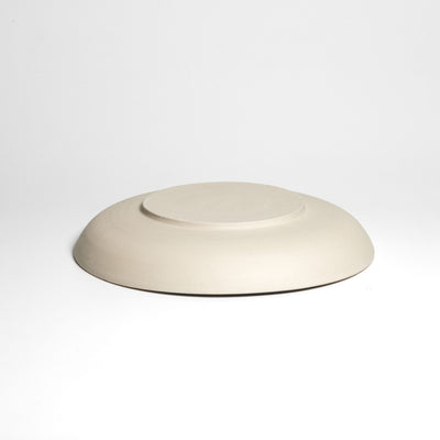 Weite flache cremefarbene Schale – Unterseite.