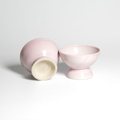 Roséfarbene Dessertschale auf kleinem Fuß – Unterseite neben aufrechter Schale.