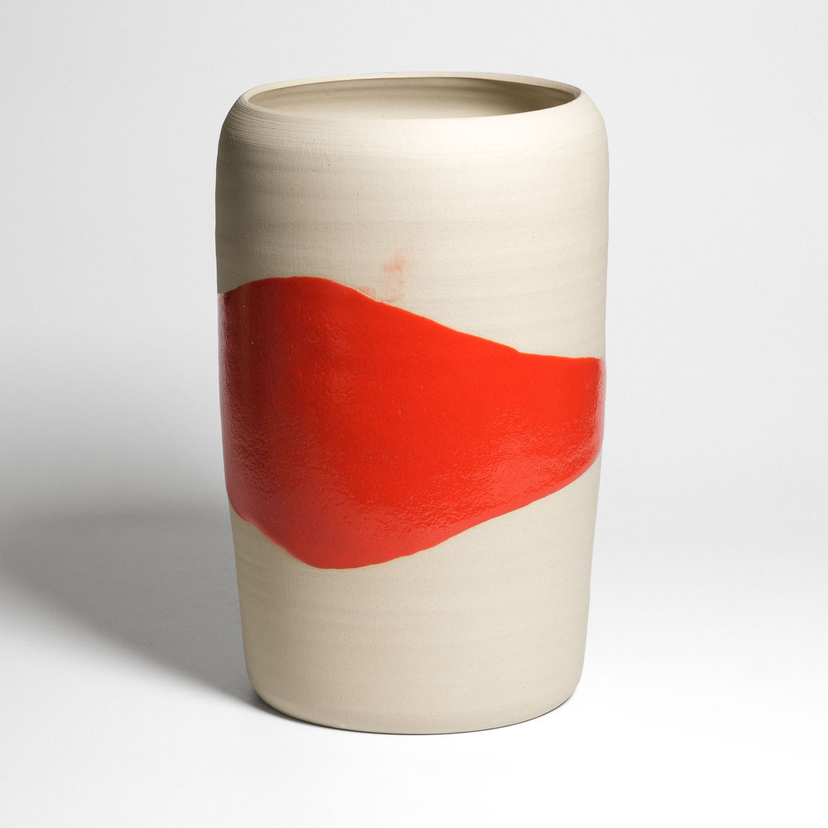 Hohe Zylindervase mit roter Splash-Glasur auf hellem Ton – Vorderansicht mit breitem rotem Band.