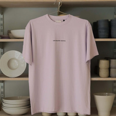 Lilac vbc Team Shirt hanging on a rack, showcasing a minimalist design with logo print.