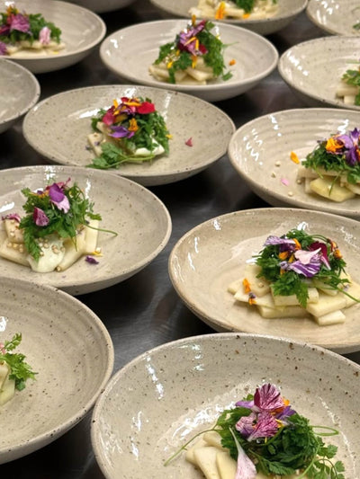Supper Club mit Dorsia & Rayas - 3-Gang Menü Dinner Veranstaltung mit kunstvoll angerichtetem Salat auf Tellern.