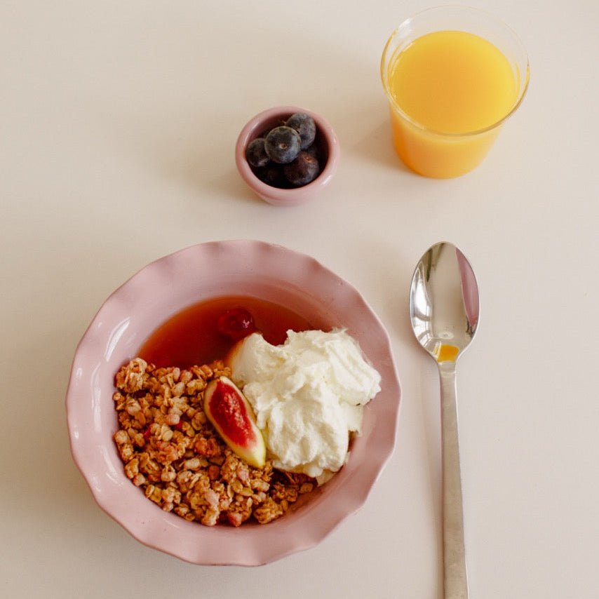Handgemachte Keramik Frühstücksschale mit Müsli, Früchten und Sahne, orange Saft daneben.