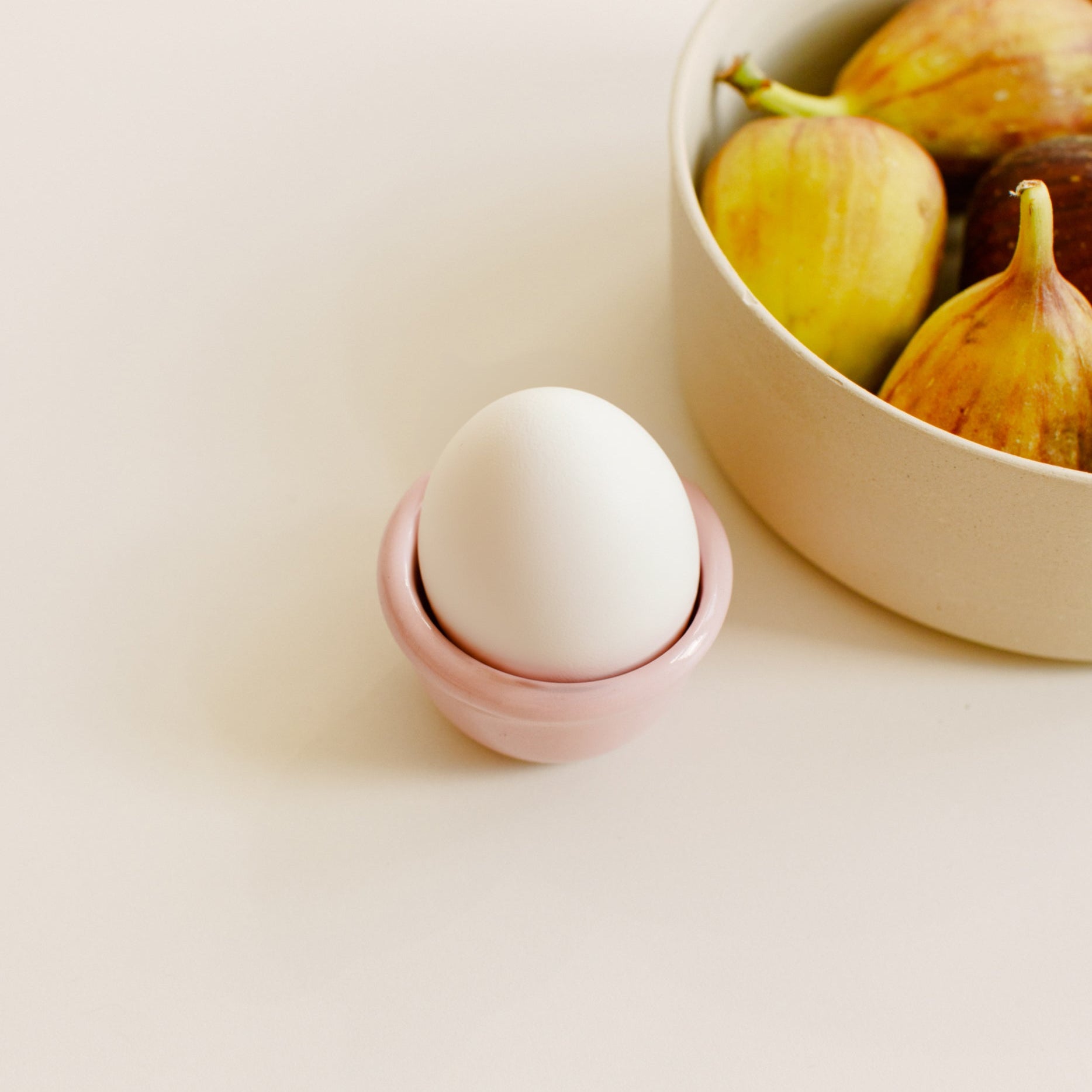 Handgemachtes Frühstücksset mit rosa Eierbecher und einer Wavy Schale mit frischen Feigen.