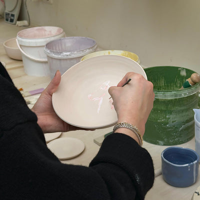Teilnehmerin beim Glasur Workshop Frankfurt malt auf einer Keramiktellerfläche.