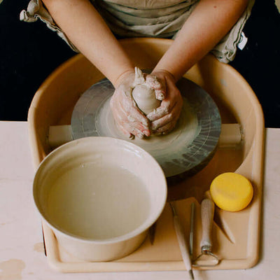 Töpferkurs für Einsteiger: Hände formen Ton auf einer Drehscheibe in der Keramikwerkstatt.