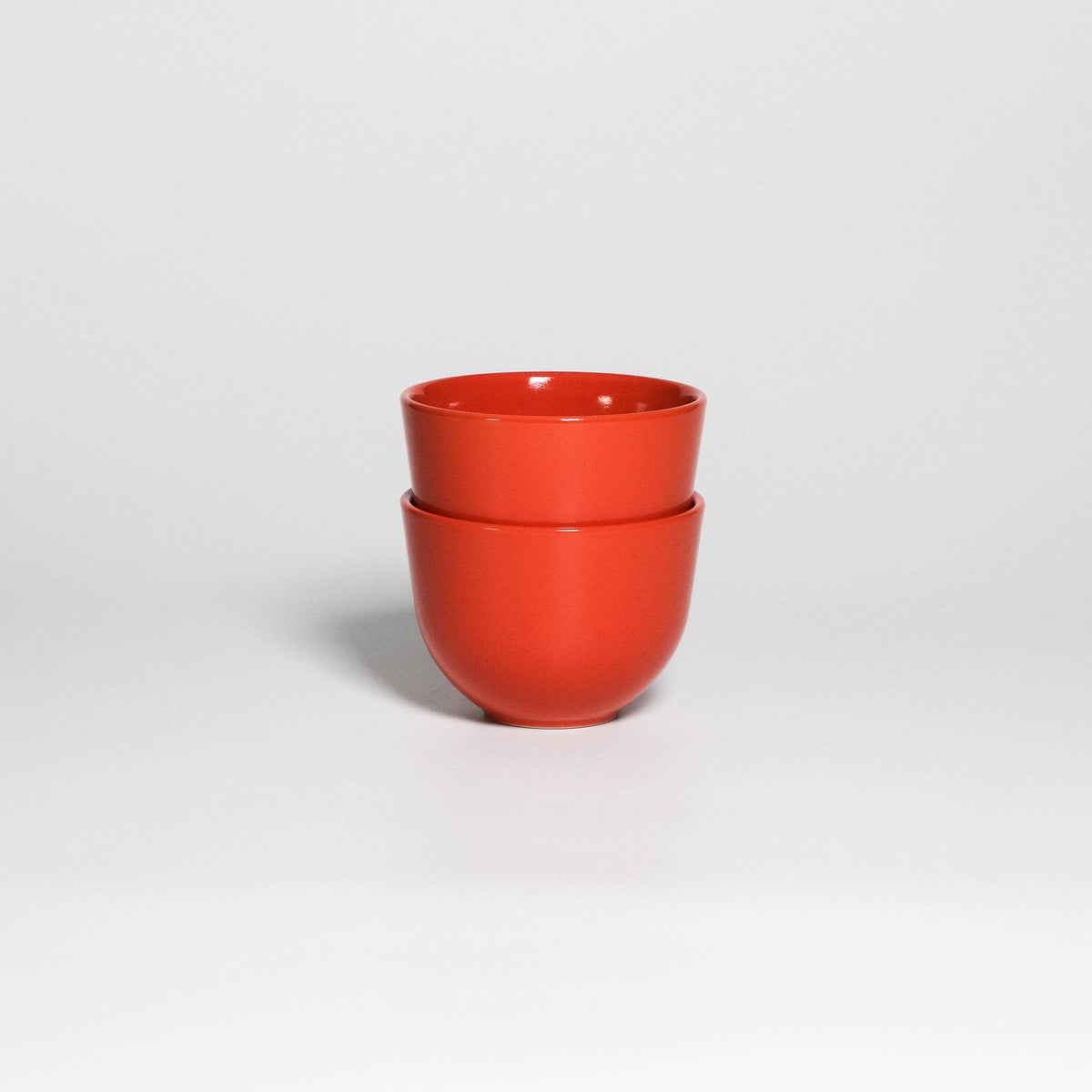 Two Coffee Cups Yun Orange stacked, handleless stoneware cups with glossy orange glaze