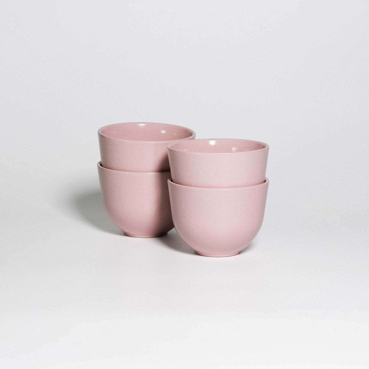 Set of 4 Coffee Cups Yun Pink, four handleless stoneware cups stacked in two pairs, glossy soft pink glaze