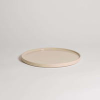 Unique creme dinner plate handcrafted from durable stoneware ceramic with a glossy finish.